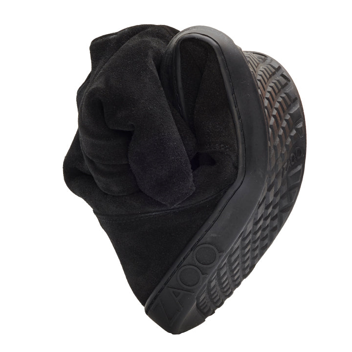 Een paar Flip-Flop-sandalen 'TUQ Black' van ZAQQ van zwart suède, in een artistieke en sculpturale vorm vervaardigd, die het gestructureerde zoolpatroon en de banddetails benadrukt en zo hun unieke flexibiliteit en ontwerp benadrukt.