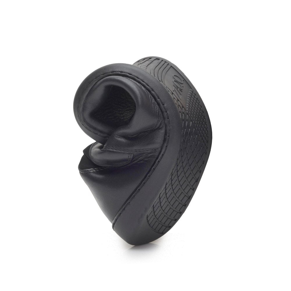 De SELEQT Stretch Black slipper van ZAQQ buigt om zijn flexibiliteit te demonstreren. De zool is voorzien van een gestructureerd patroon voor betere grip. Verticaal gepositioneerd op een eenvoudige witte achtergrond, benadrukt het het flexibele en duurzame ontwerp van de schoen.