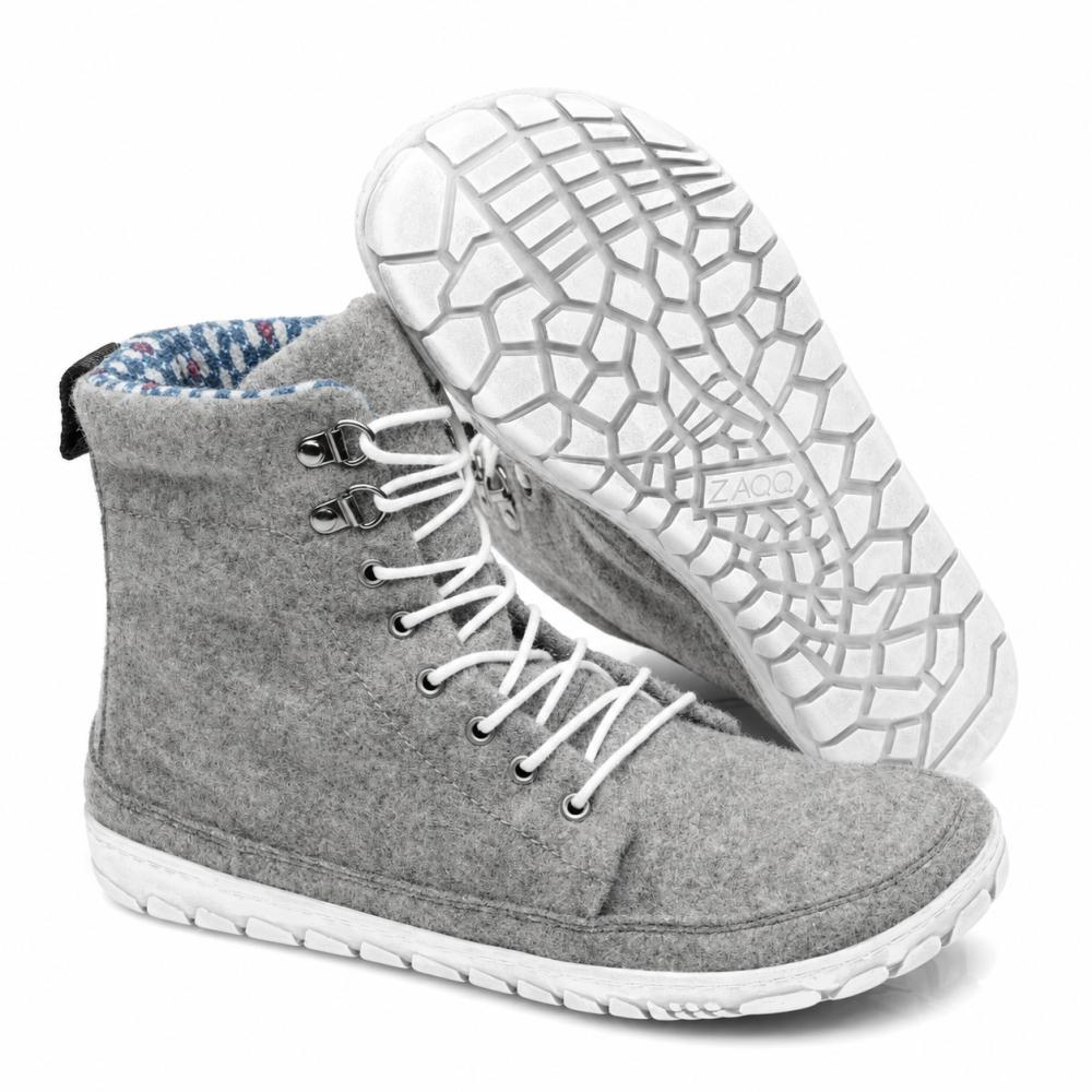Uitgestald staat een paar QICE Grey High-Top-Sneakers van ZAQQ met witte veters. Eén schoen staat rechtop, terwijl de andere schuin is geplaatst om de gestructureerde, gemodelleerde outdoorschoen te benadrukken.