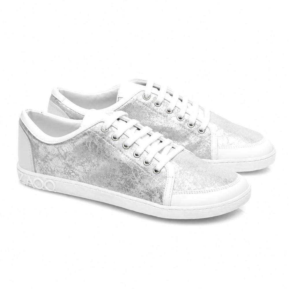 Wij presenteren de TIQQ Silver White van ZAQQ: Een paar stijlvolle sneakers van hoogwaardig nappaleer met een opvallende metallic-zilveren textuur en witte zolen. Deze sneakers zijn uitgerust met stralend witte veters, siernaden en een markant 4000-detail aan de zijkant van de zool.