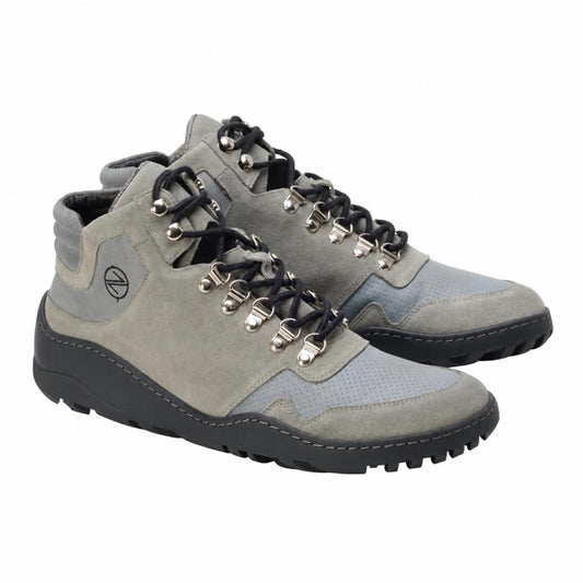 Die grauen, wasserdichten VAQATION-Stiefel von ZAQQ sind für Outdoor-Aktivitäten konzipiert und verfügen über eine robuste, flexible Sohle und schwarze Schnürsenkel, die durch Metallösen geführt werden. Sie haben einen gepolsterten Knöchelkragen für zusätzlichen Komfort und tragen das aufgenähte Markenlogo an der Seite. Diese grauen Wanderstiefel sind außerdem wasserdicht.